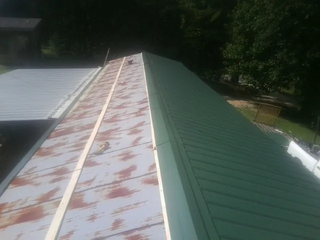 Old rusted panels beside newly installed green metal roofing — Wind Damage Roof Repair by Roofing Brothers in Carmel