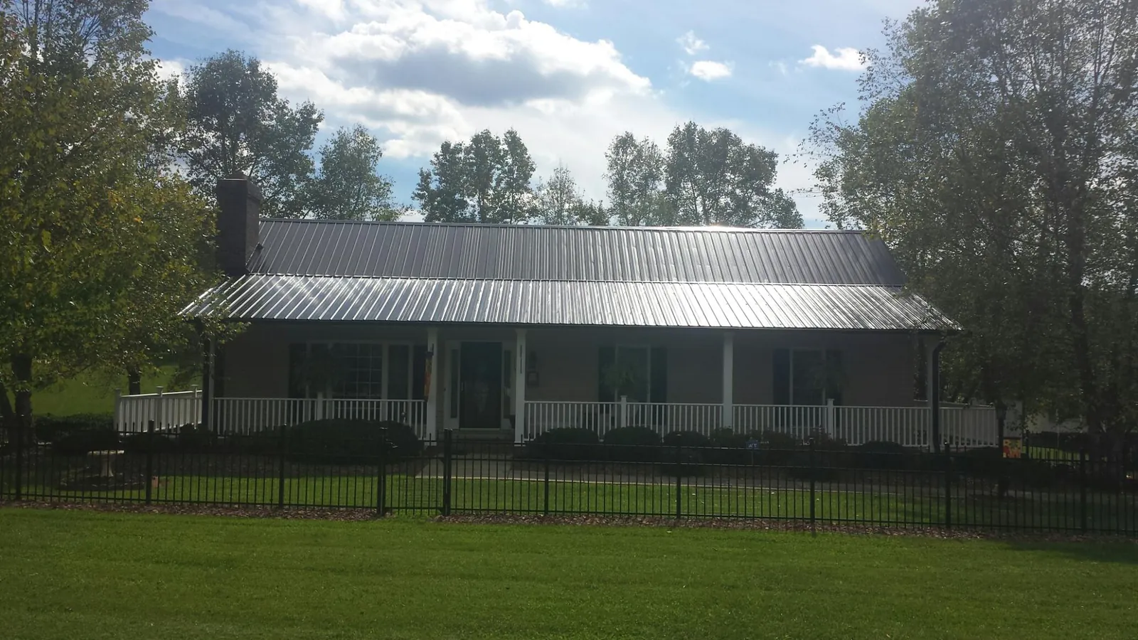 Gray metal roof on a brick ranch with a full width front porch — Gutter Guard Installation work by our crew in Carmel